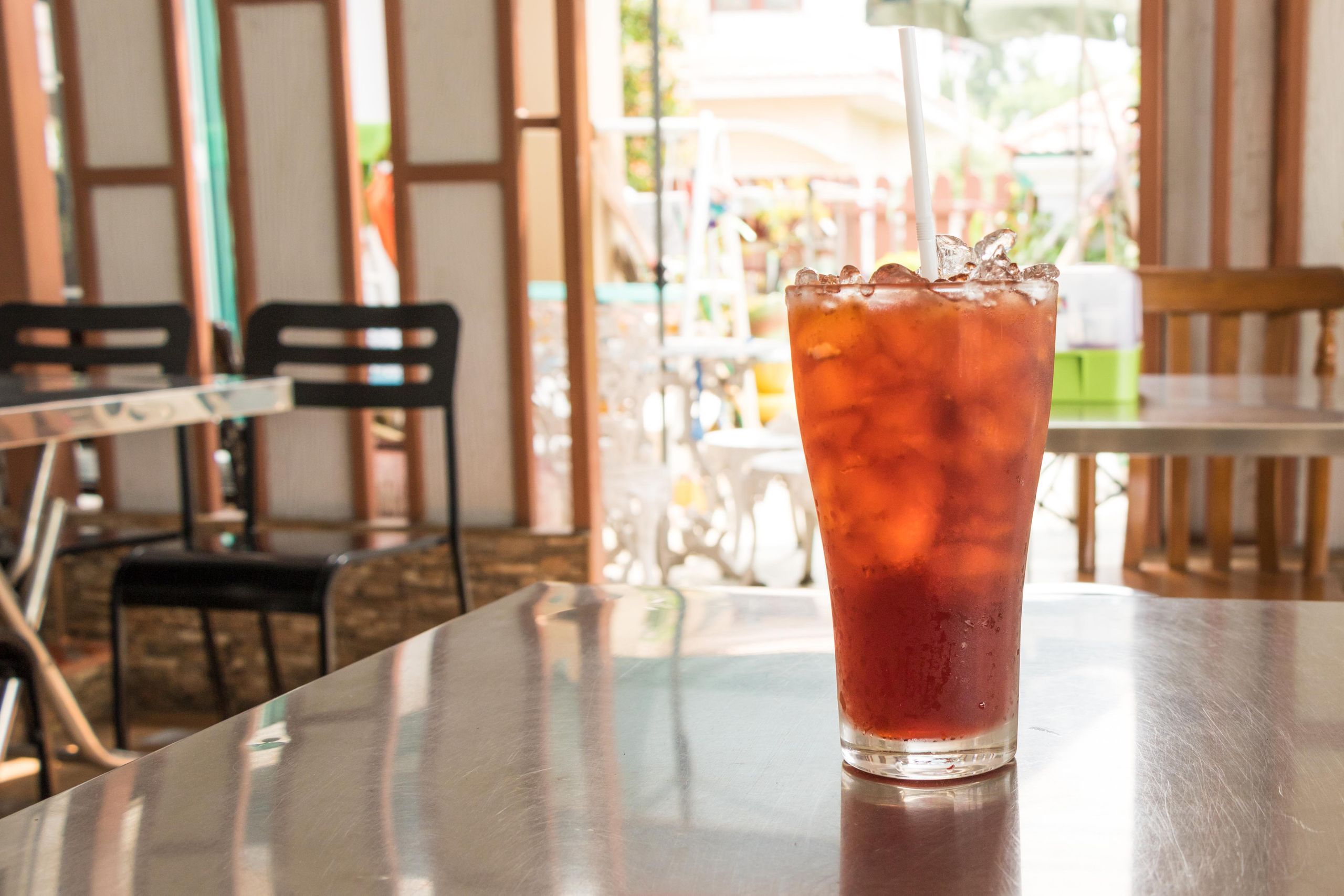 Refreshing iced tea in a glass with straw on a cafe table, perfect for summertime.