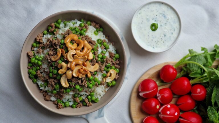 Rice with peas and cashews, served with fresh radishes and yogurt sauce for a nutritious meal.
